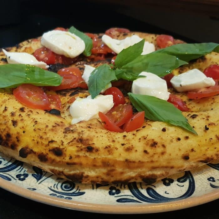 Une pizza frite napolitaine avec du basilic, mozzarella, tomate et huile d'olives dessus